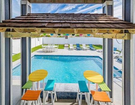 a pair of picnic tables underneath a pergola facing a private pool